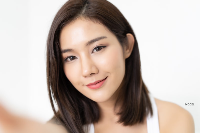 Pleased Asian woman smiling at camera.