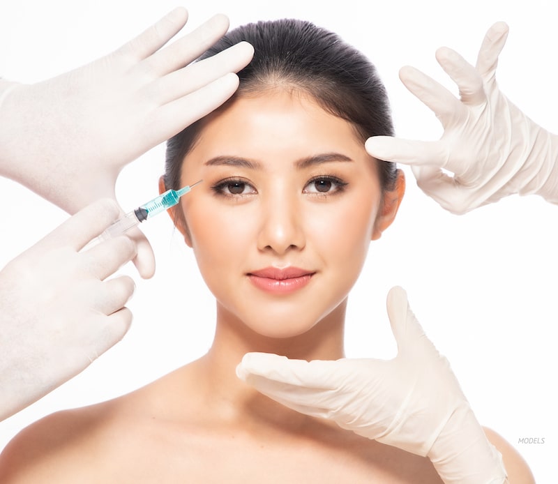 Young Asian women getting an injectable treatment at the corner of her eye.