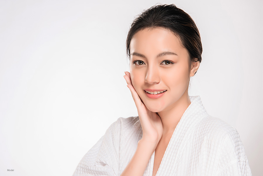 Beautiful Asian woman feels her smooth skin.